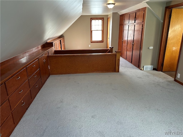 bonus room with lofted ceiling and light colored carpet