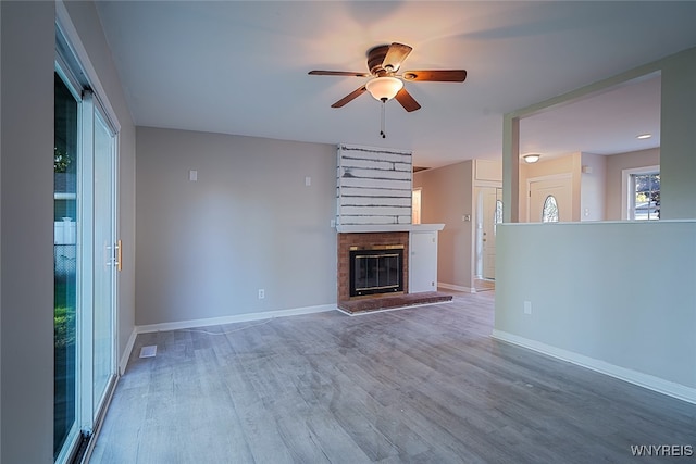 unfurnished living room featuring a brick fireplace, hardwood / wood-style flooring, and ceiling fan