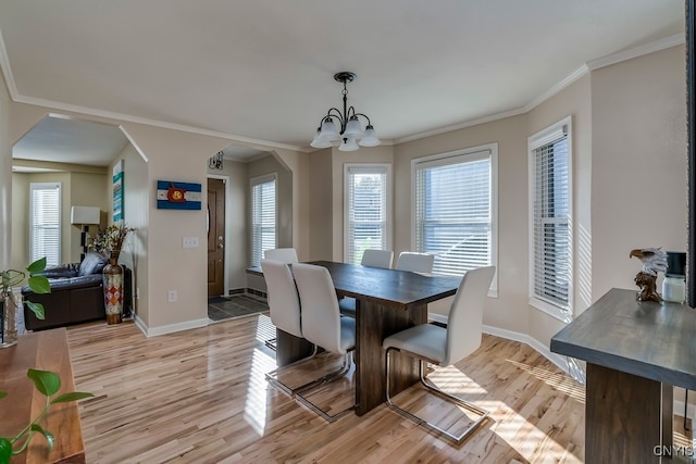 dining area with ornamental molding, light hardwood / wood-style flooring, and an inviting chandelier