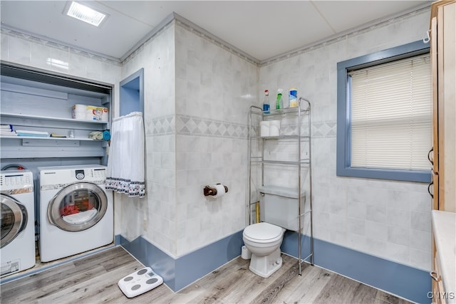 laundry area featuring light hardwood / wood-style floors, tile walls, and separate washer and dryer