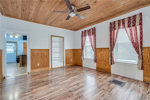 empty room featuring a wealth of natural light, light hardwood / wood-style flooring, wood ceiling, and built in shelves