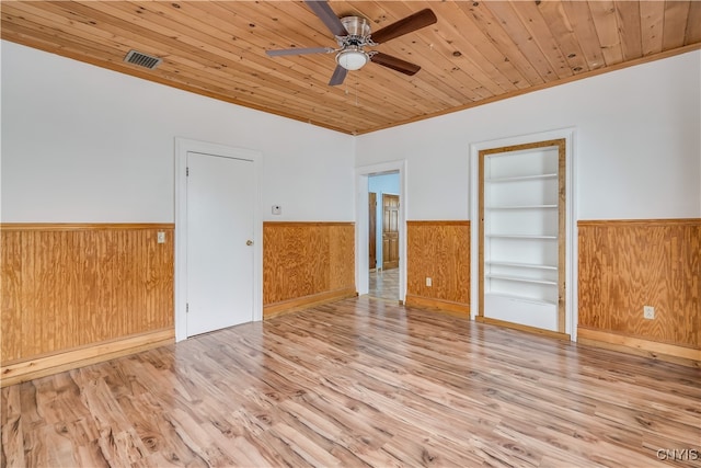 spare room with light hardwood / wood-style floors, ceiling fan, built in features, and wooden ceiling