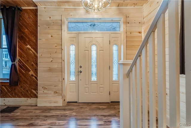 entrance foyer with an inviting chandelier, hardwood / wood-style floors, a healthy amount of sunlight, and wood walls