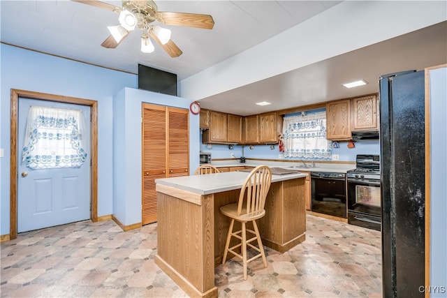 kitchen featuring a kitchen island, a kitchen breakfast bar, sink, black appliances, and ceiling fan