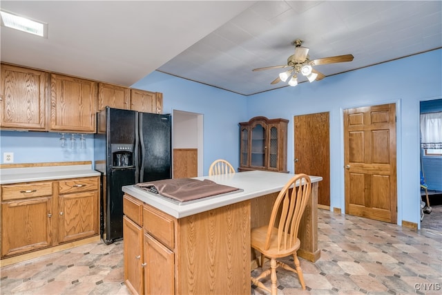 kitchen featuring a breakfast bar area, a center island, ceiling fan, and black fridge