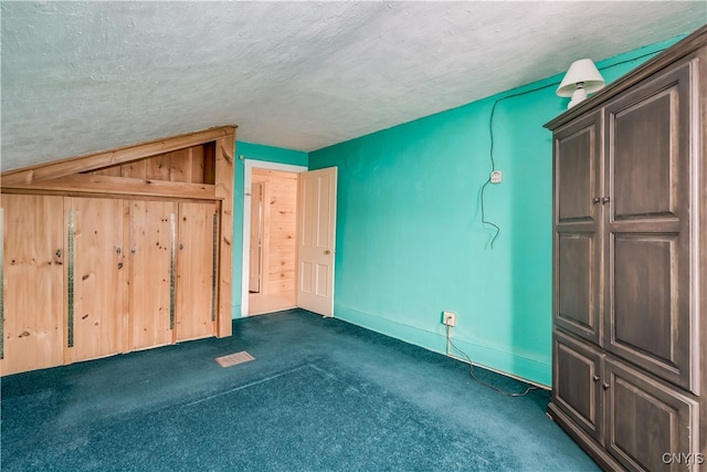 bonus room featuring dark colored carpet and a textured ceiling