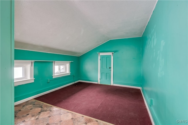 carpeted empty room featuring lofted ceiling and a textured ceiling