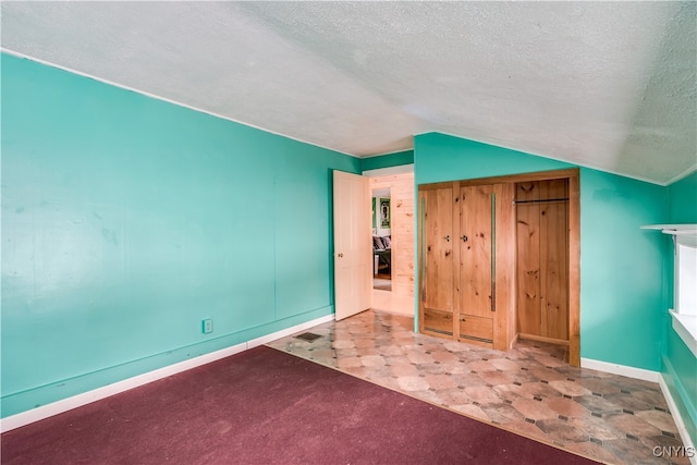 unfurnished bedroom with a textured ceiling and vaulted ceiling