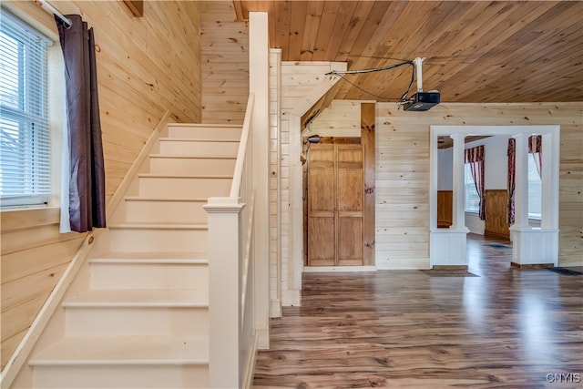 stairs with wood ceiling, hardwood / wood-style flooring, ornate columns, and wood walls