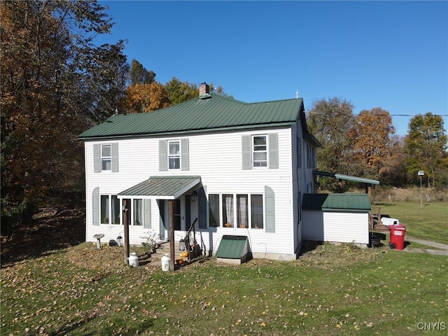rear view of property featuring a yard and metal roof
