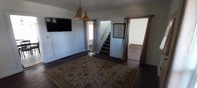 entrance foyer with dark wood-type flooring, a wealth of natural light, and an inviting chandelier