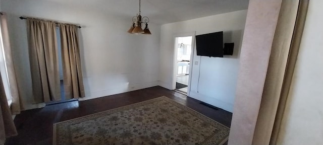 empty room with an inviting chandelier and dark hardwood / wood-style flooring