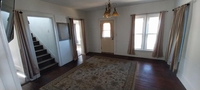 entrance foyer featuring dark wood-type flooring, a notable chandelier, and a wealth of natural light