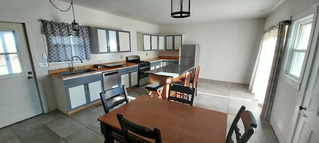 kitchen featuring sink, light tile patterned flooring, decorative light fixtures, and stainless steel appliances