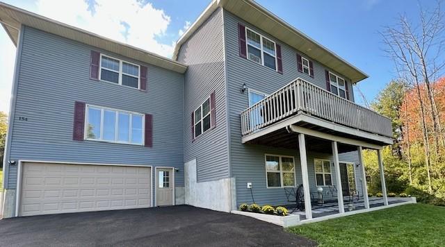 back of property with a yard, a balcony, and a garage