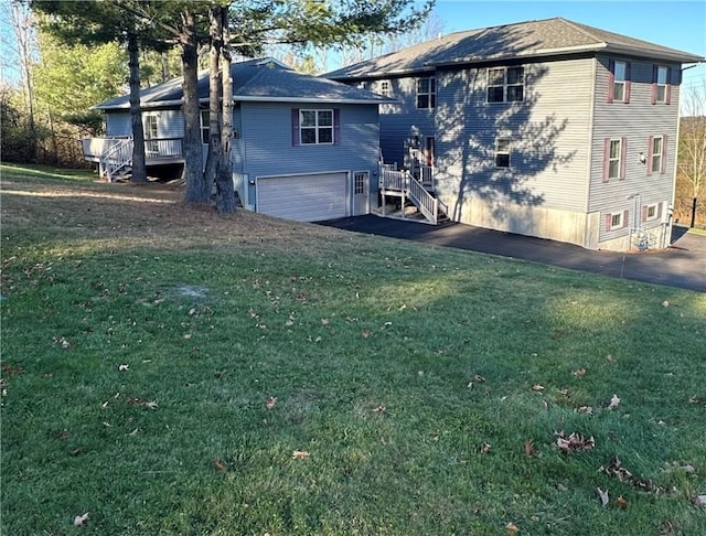 back of property featuring a garage, a yard, and a wooden deck