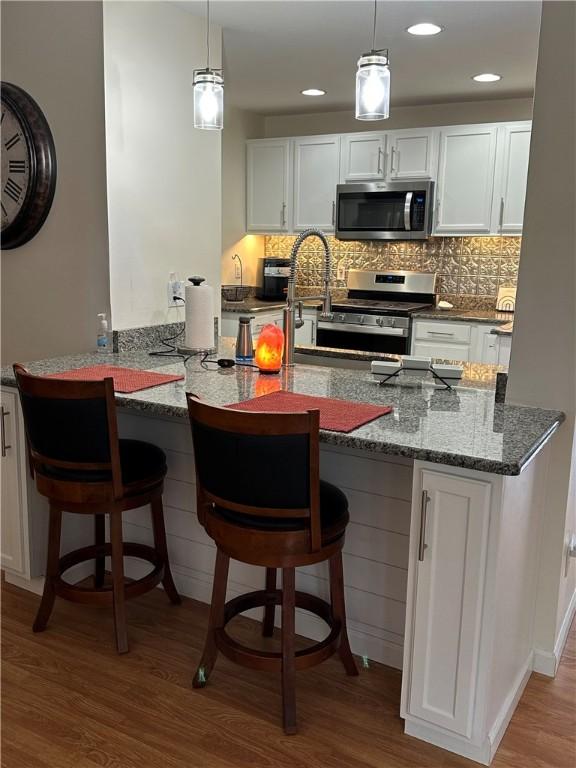 kitchen featuring hardwood / wood-style floors, white cabinets, and stainless steel appliances