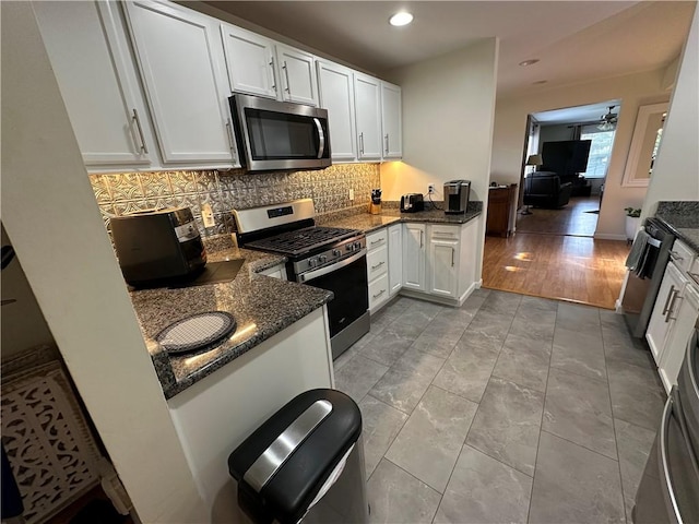 kitchen featuring stainless steel appliances, backsplash, dark stone counters, light hardwood / wood-style floors, and white cabinets