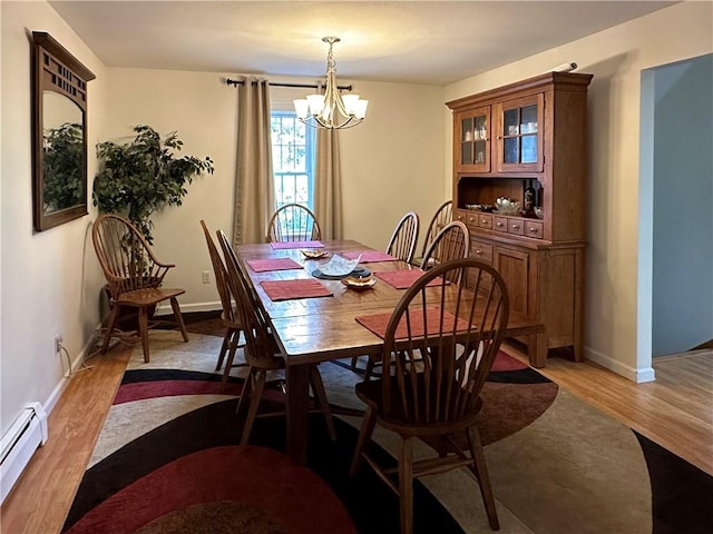 dining room with an inviting chandelier, baseboard heating, and light hardwood / wood-style flooring