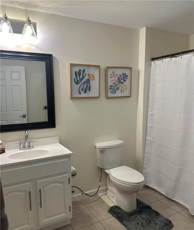 bathroom with tile patterned flooring, vanity, toilet, and a textured ceiling