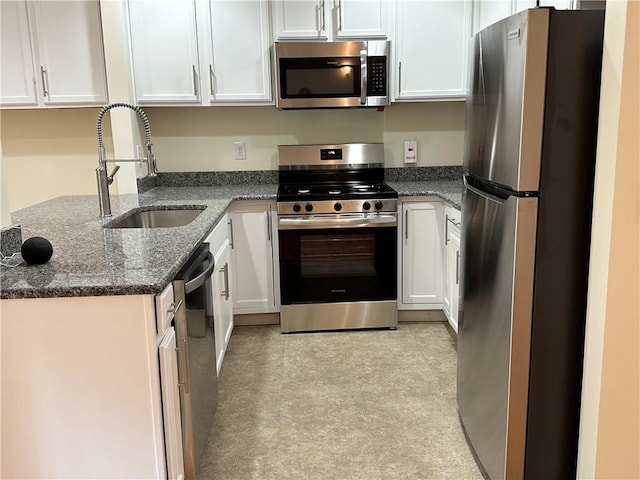 kitchen featuring white cabinets, stainless steel appliances, dark stone counters, and sink