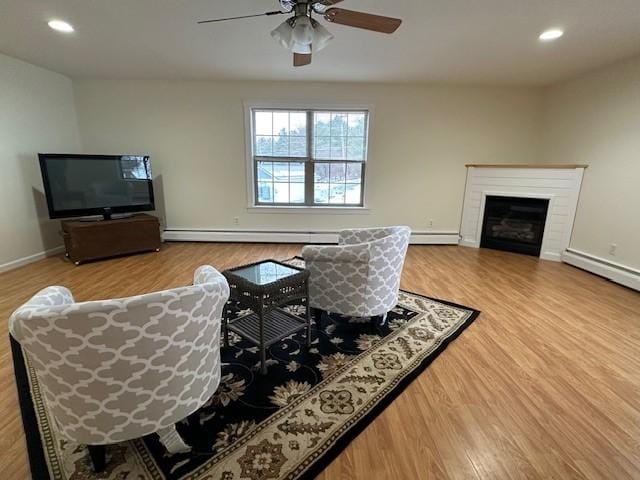 living room with ceiling fan, a baseboard radiator, and hardwood / wood-style flooring