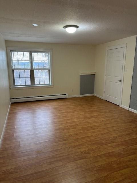 empty room with wood-type flooring and baseboard heating