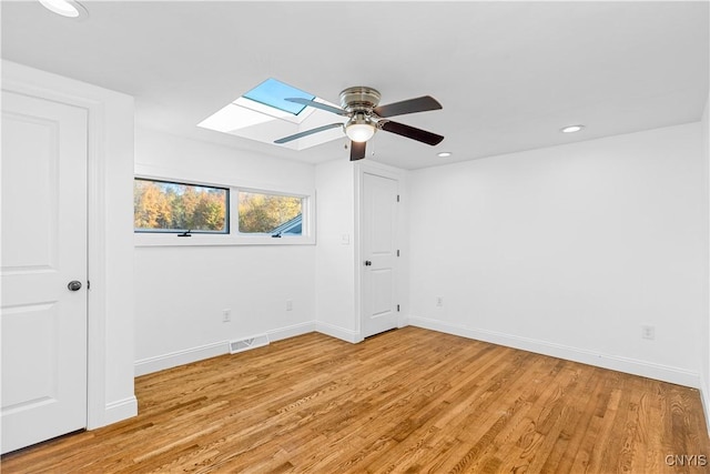 9869 Hazard Rd, Marcy, NY 13403 - spare room featuring a ceiling fan, a skylight, light wood-type flooring, baseboards, and recessed lighting