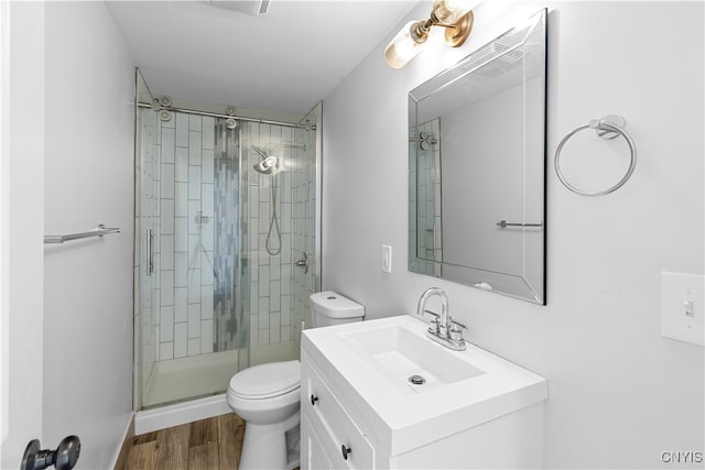 bathroom featuring hardwood / wood-style flooring, a shower with door, vanity, and toilet