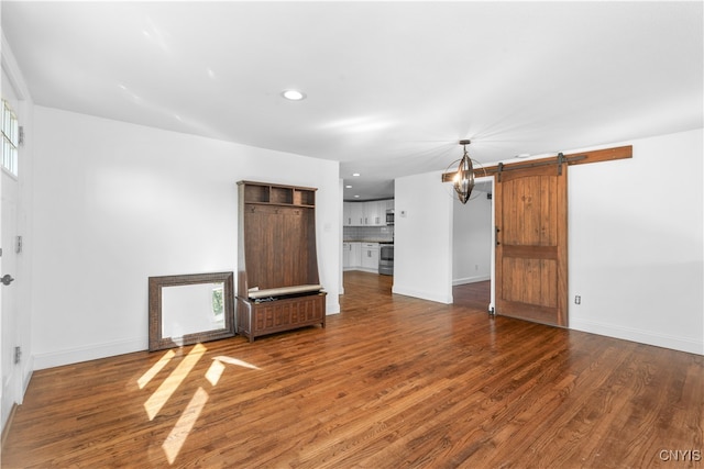 unfurnished living room with a barn door and dark hardwood / wood-style floors