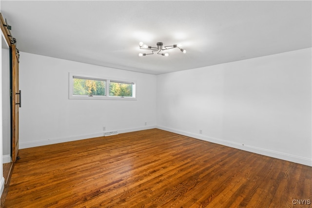 empty room featuring a barn door and wood-type flooring