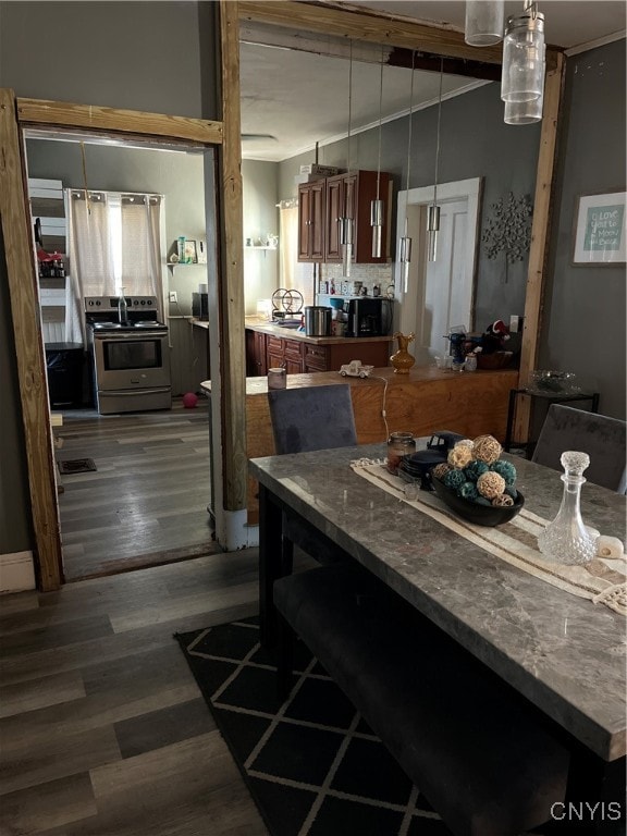 kitchen with stainless steel electric range, wood-type flooring, decorative light fixtures, and a kitchen breakfast bar