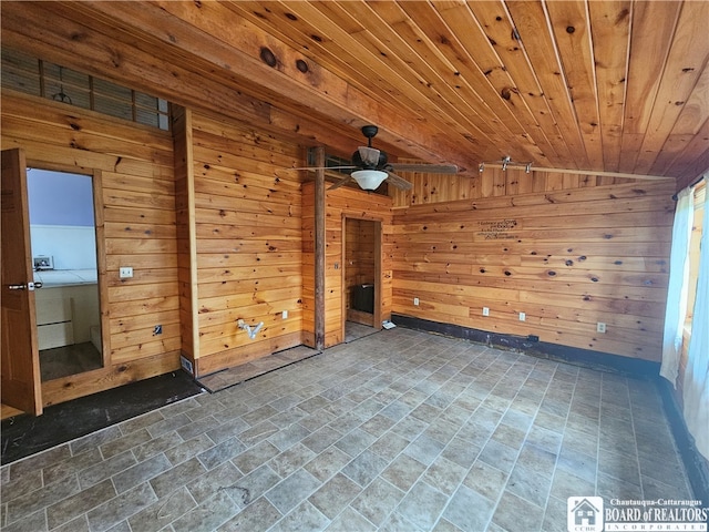 unfurnished living room featuring wood walls, wooden ceiling, vaulted ceiling, and ceiling fan