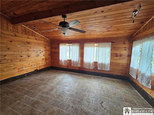 empty room with wooden walls, vaulted ceiling, ceiling fan, and wooden ceiling