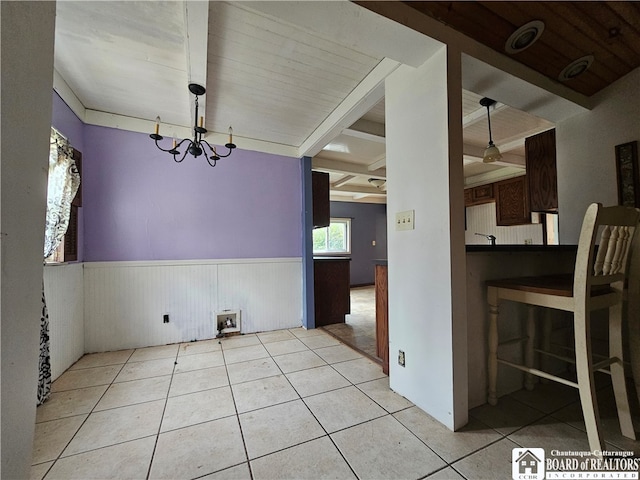 unfurnished dining area featuring beamed ceiling, an inviting chandelier, and light tile patterned floors