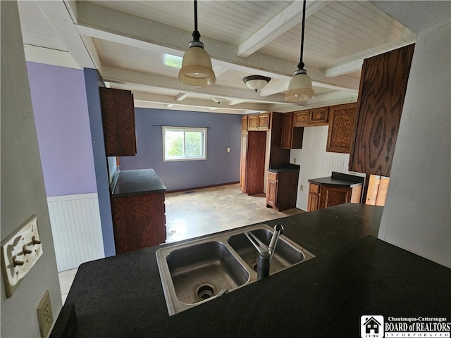 kitchen featuring decorative light fixtures, beam ceiling, and sink