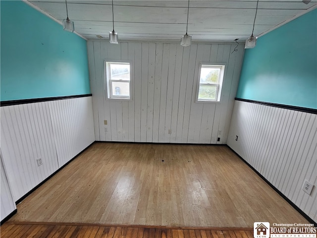 empty room featuring light wood-type flooring and wood walls