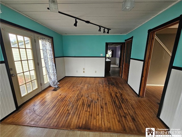 empty room with hardwood / wood-style floors and rail lighting