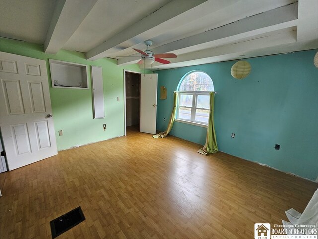 unfurnished room featuring beam ceiling, wood-type flooring, and ceiling fan