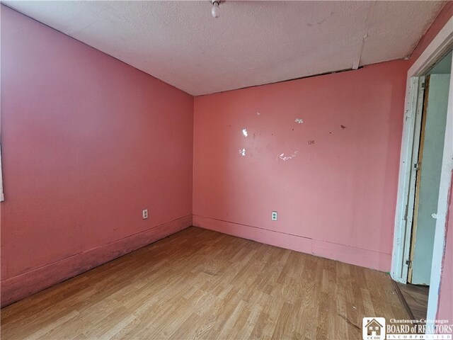 empty room with light hardwood / wood-style floors and a textured ceiling