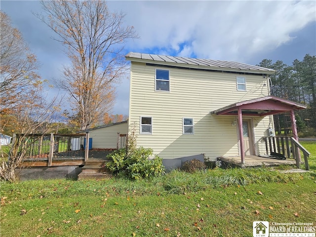 rear view of property featuring a wooden deck and a lawn