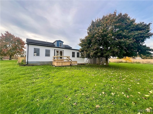 rear view of property with a wooden deck and a lawn