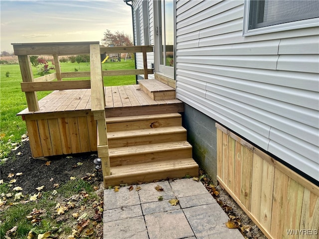 deck at dusk featuring a lawn