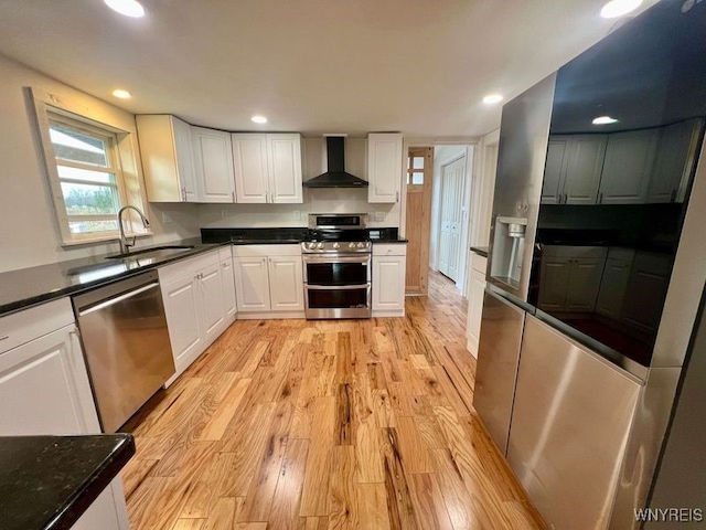 kitchen featuring sink, light hardwood / wood-style floors, stainless steel appliances, wall chimney exhaust hood, and white cabinets