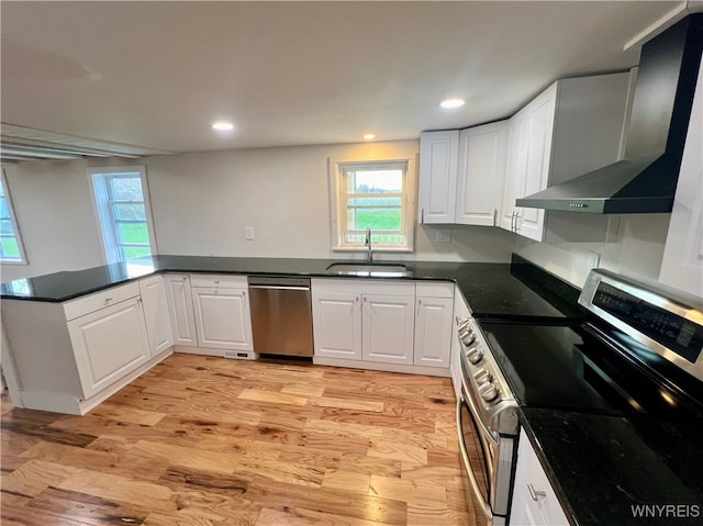 kitchen featuring white cabinetry, light hardwood / wood-style floors, appliances with stainless steel finishes, and wall chimney range hood