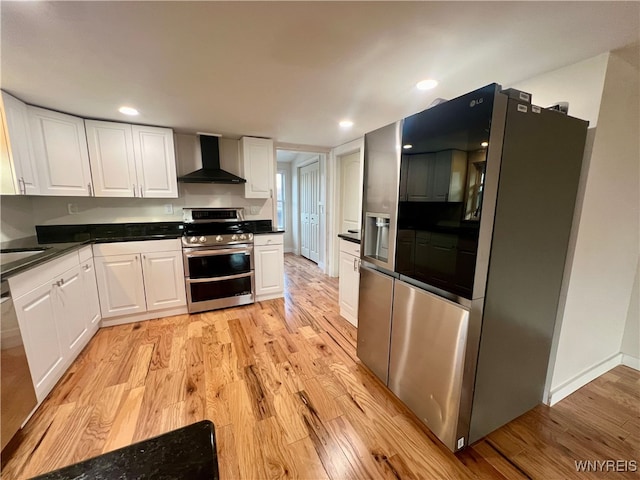 kitchen with wall chimney range hood, white cabinetry, stainless steel appliances, and light hardwood / wood-style floors