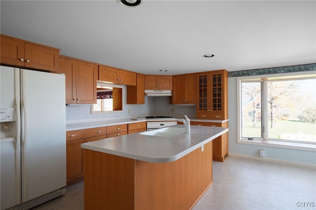 kitchen featuring a center island with sink, sink, and white refrigerator with ice dispenser