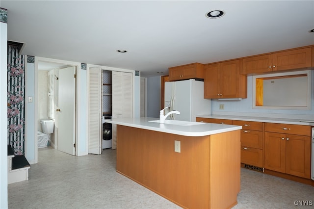 kitchen featuring sink, washer / clothes dryer, white refrigerator with ice dispenser, and an island with sink