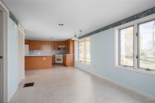 kitchen with sink, kitchen peninsula, decorative light fixtures, and white appliances