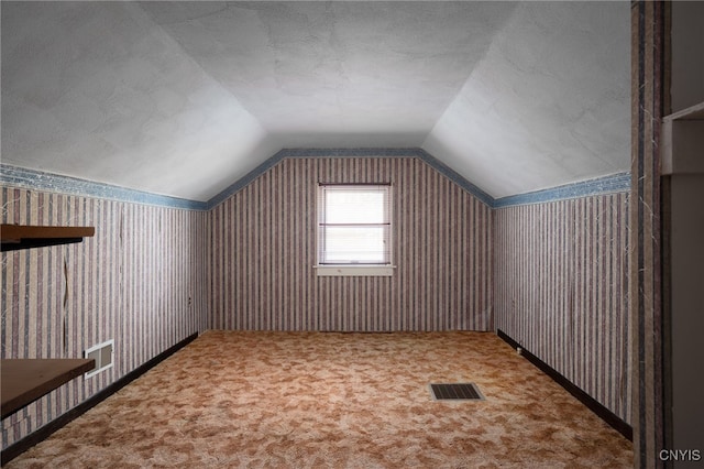 bonus room with lofted ceiling and carpet flooring